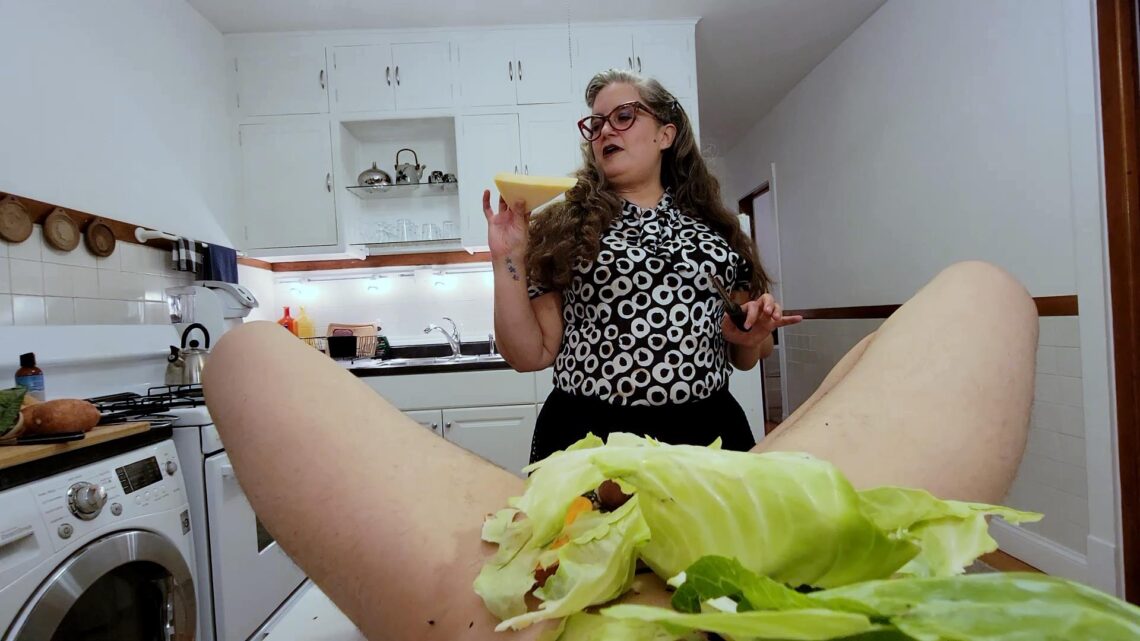 Looking over a body covered in cabbage and other vegetable, woman in background holding parmesan cheese rind